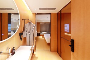 Een hotelkamer met een badkamer, een bed, een zithoek en een spiegel.
