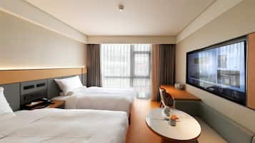 Une chambre d’hôtel avec deux lits, un bureau, une télévision et une grande fenêtre.