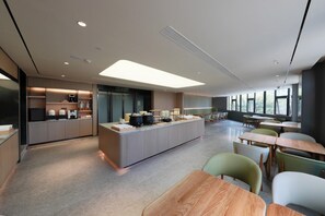 A modern kitchen with a central island, built-in appliances, and a dining area with tables and chairs.