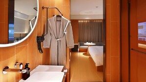 A modern hotel bathroom with a large mirror, a sink, and a robe hanging on a rack. - Ji Hotel (xiamen Haicang District Government Branc (Xiamen)