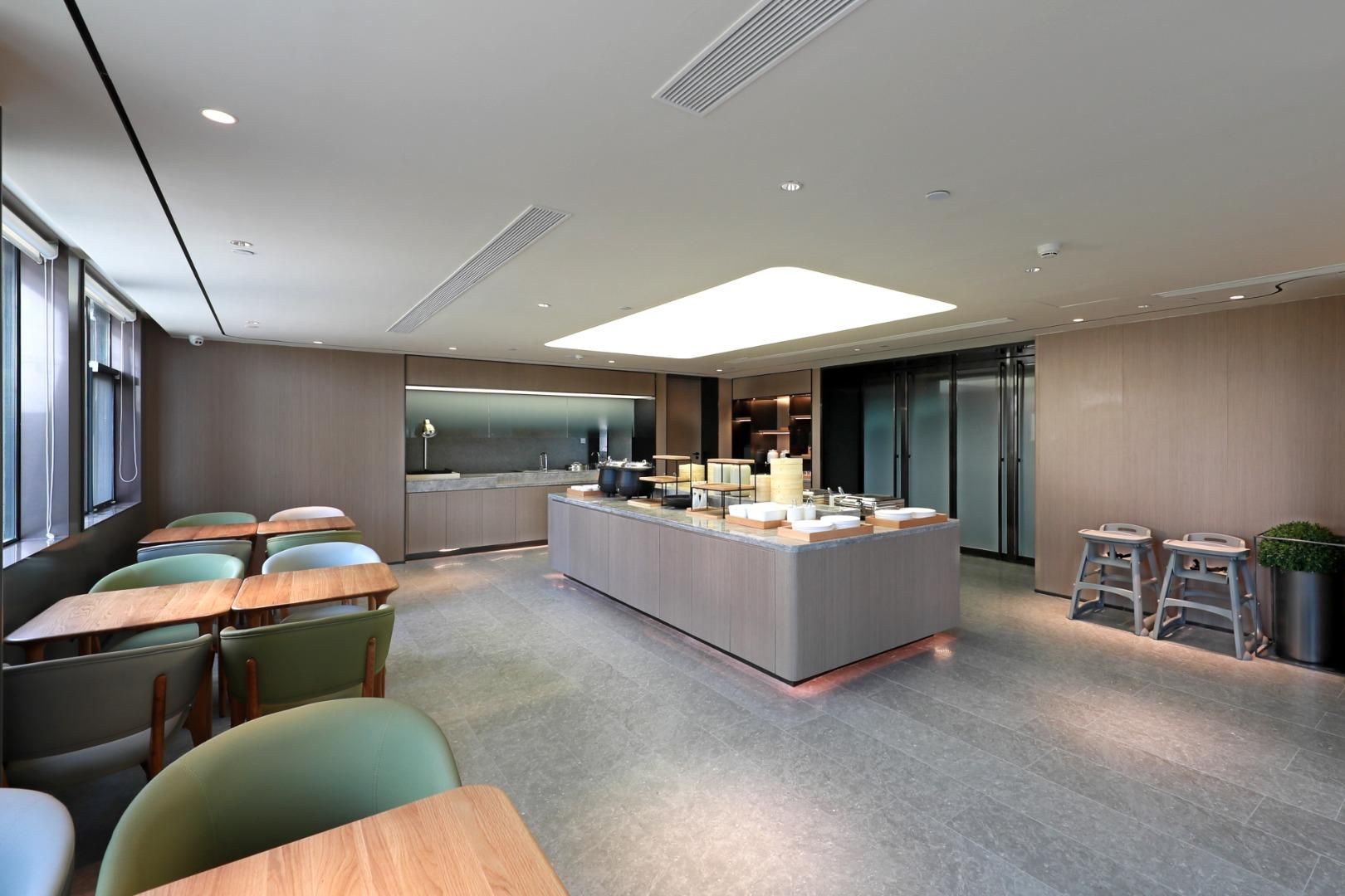 Un espace cuisine moderne doté d’un îlot central, de tabourets de bar et d’un coin salon avec des tables et des chaises.