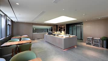 Un espace cuisine moderne doté d’un îlot central, de tabourets de bar et d’un coin salon avec des tables et des chaises.