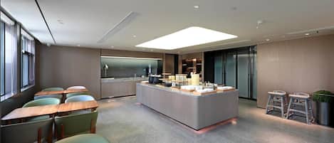 A modern kitchen area with a central island, bar stools, and a seating area with tables and chairs.