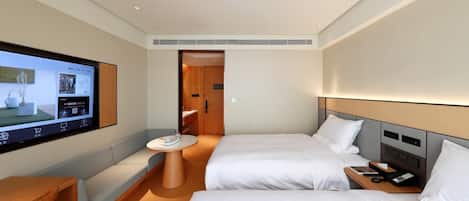A hotel room with two beds, a TV, a small table, and a bedside table with a phone.