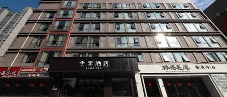 Un hôtel à plusieurs étages doté d’une façade moderne, avec une entrée imposante et une enseigne bien visible.