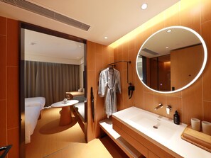 A modern hotel bathroom with a large mirror, a vanity with a sink, and a robe hanging on a rack. - Ji Hotel (xiamen Haicang District Government Branc (Xiamen)