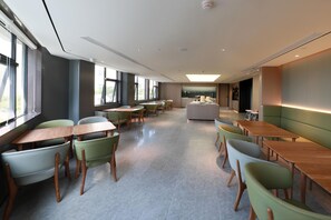 Un comedor moderno con varias mesas y sillas, ventanas amplias y una isla central.