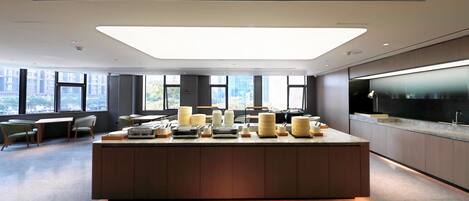 A modern kitchen with a central island, large windows, and a view of the city.