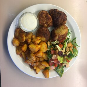A plate with fried food, a salad, and a small bowl of sauce.