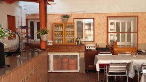 A kitchen with a tiled backsplash, a wooden counter, a sink, a stove, and a dining area with a table and chairs. - Lo Mirador - Poble Nou (Poblenou del Delta)