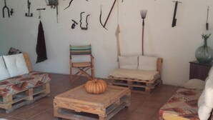 A rustic room with a wooden coffee table, a striped chair, and a bed with a striped blanket. - Lo Mirador - Poble Nou (Poblenou del Delta)