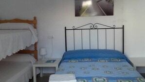 A room with a bunk bed, a single bed, a bedside table with a lamp, and a wall-mounted picture. - Lo Mirador - Poble Nou (Poblenou del Delta)