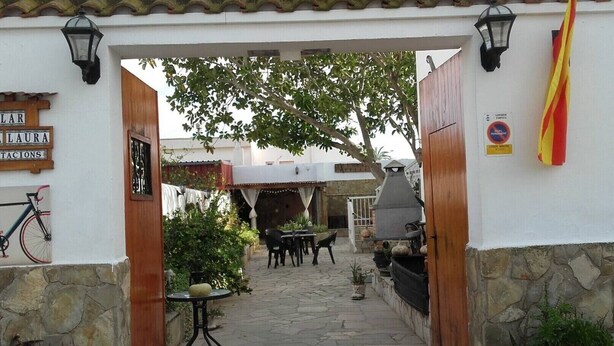 An outdoor patio area with stone flooring, tables, chairs, and a grill. - Lo Mirador - Poble Nou (Poblenou del Delta)