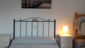 Een slaapkamer met een metalen bedframe, een nachtkastje met een lamp, en een wanddecoratie.