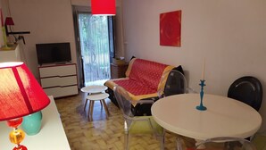 Een gezellige kamer met een televisie, een rode lamp, een bank, een tafel en een stoel.