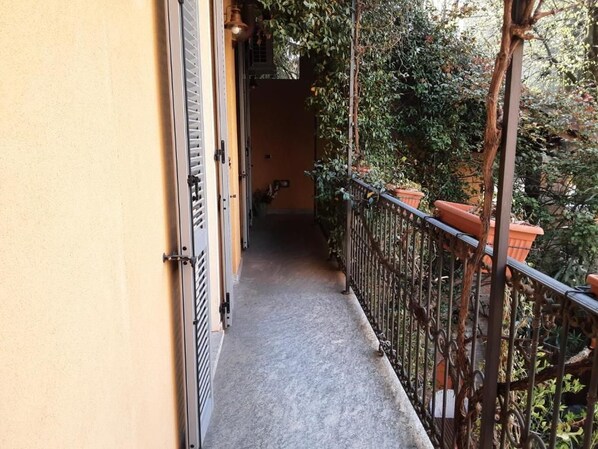 A narrow balcony with a metal railing, potted plants, and a door leading to an interior space. - B&B Corte delle Rose (Voghera)