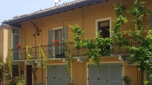 Un edificio con fachada amarilla, antena parabólica y entrada protegida por una reja.