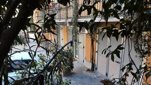 Un estrecho callejón con plantas en macetas y una puerta de metal.