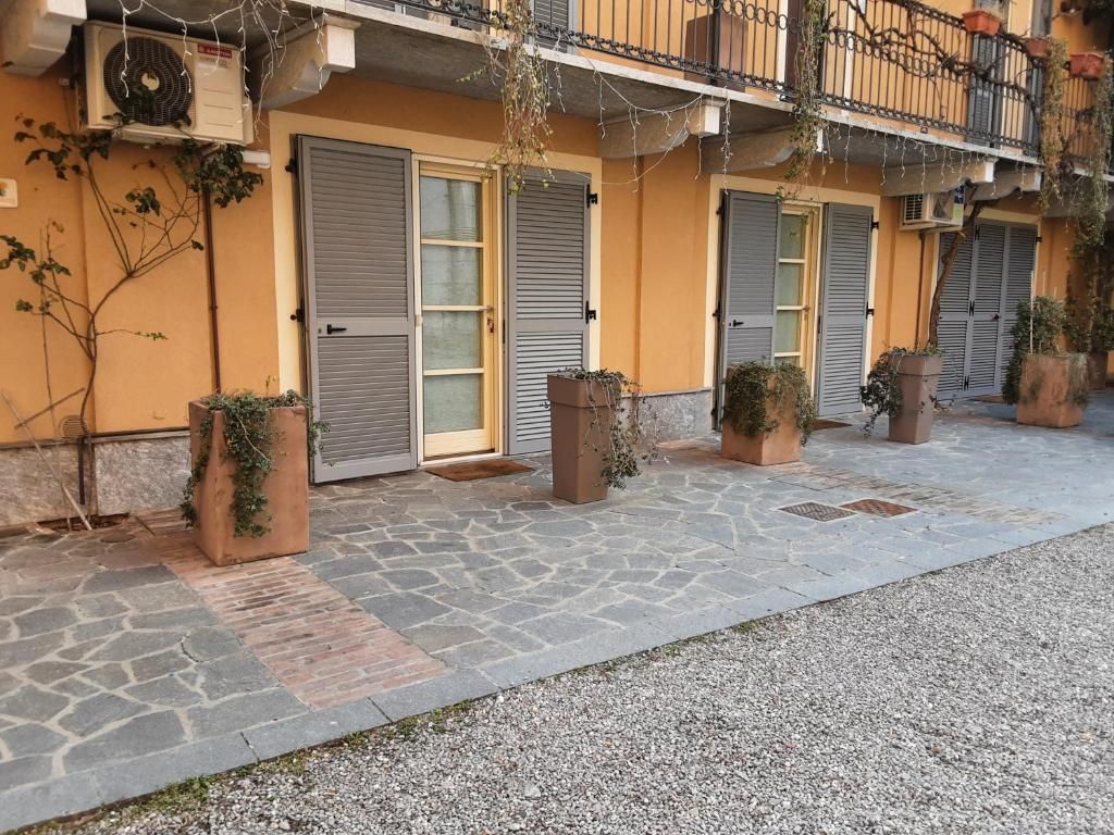A building with closed shutters, potted plants, and a stone-paved ground.