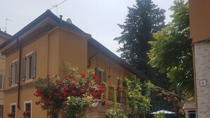 Un edificio de dos pisos con fachada amarilla, entrada de ladrillo y portón de metal.