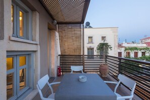 A balcony with a table and chairs, a fire extinguisher, and a potted plant.