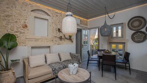 A cozy living area with a stone wall, a sofa, a coffee table, and a dining table with chairs. - In the old historical town of Rethymno,Daphne Luxury Home with a private pool (Rethymno)