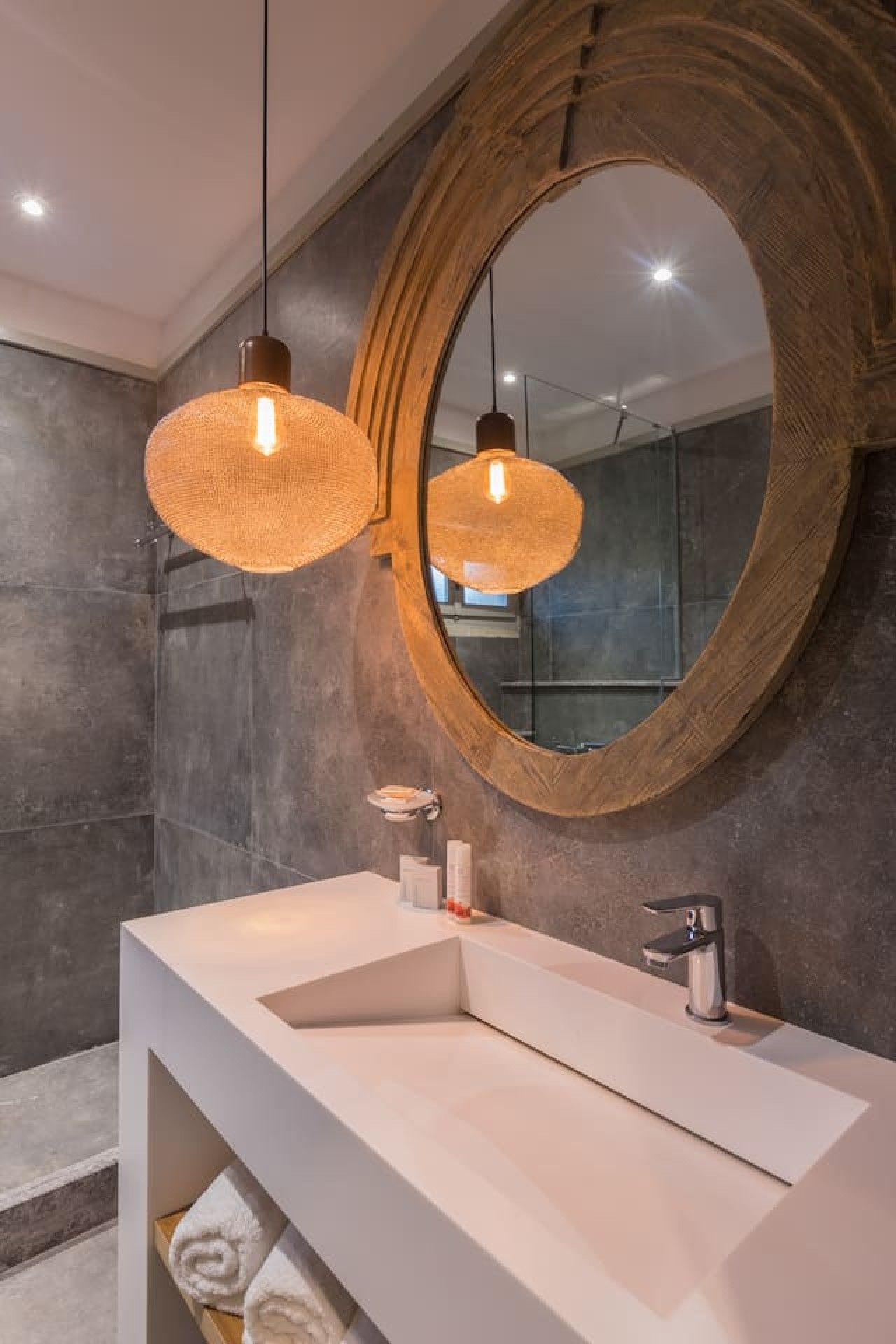 A modern bathroom with a large mirror, two hanging light fixtures, and a white vanity.