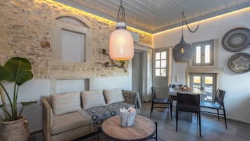 A cozy living room with a stone wall, a sofa, a coffee table, and a dining area with chairs and a table.