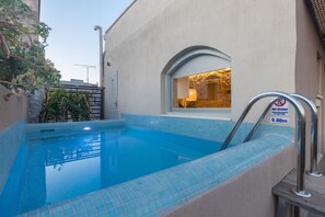 Une piscine avec un panneau indiquant qu’il est interdit de plonger, une fenêtre diffusant une lumière chaleureuse et un bord carrelé.