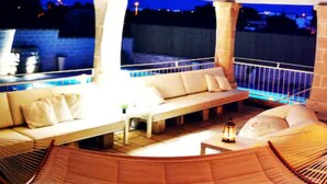 An outdoor lounge area with a pool, seating arrangements, and a hammock. - Luxury Villa Le Muse between Santa Maria al Bagno and Nardò with swimming pool and Wifi (Santa Maria al Bagno)