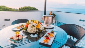 Ein gedeckter Tisch mit Meerblick, eine Champagnerflasche und eine Blumenarragemant.