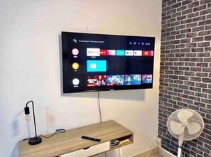 A flat-screen TV mounted on a wall with a wooden TV stand below. - Las Canteras beach studio apartment 1BR 1BTH WiFi - best position of the beach (Las Palmas de Gran Canaria)