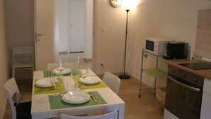 A dining area with a table set for four, a microwave, a stove, and a clock on the wall. - Casa Palladio XL, in the heart of the historic city center (Vicenza)