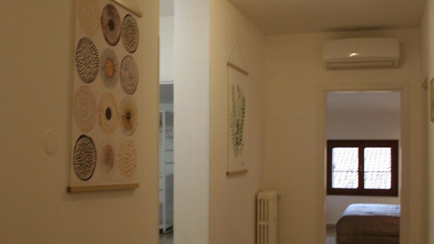 A hallway with wooden flooring, a radiator, and a bed in the background. - Casa Palladio XL, in the heart of the historic city center (Vicenza)