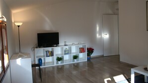 A modern living room with a white entertainment unit, a flat-screen TV, and a bookshelf. - Casa Palladio XL, in the heart of the historic city center (Vicenza)