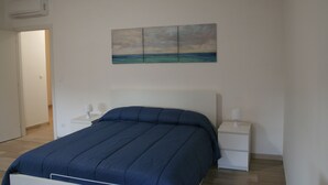 A bedroom with a bed, a nightstand, a bedside table, and a wall-mounted painting. - Casa Palladio XL, in the heart of the historic city center (Vicenza)