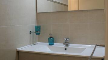 A bathroom with a sink, mirror, and cabinets.