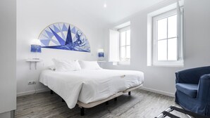 A modern bedroom with a bed, a blue chair, and a large window.