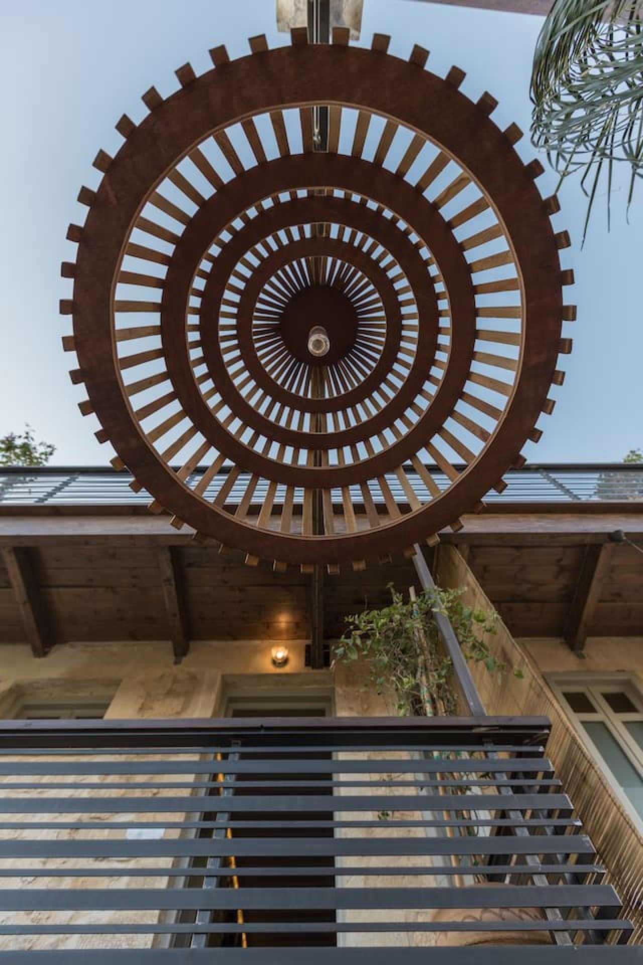 A large circular metal sculpture with a central hole, mounted on a building's exterior.