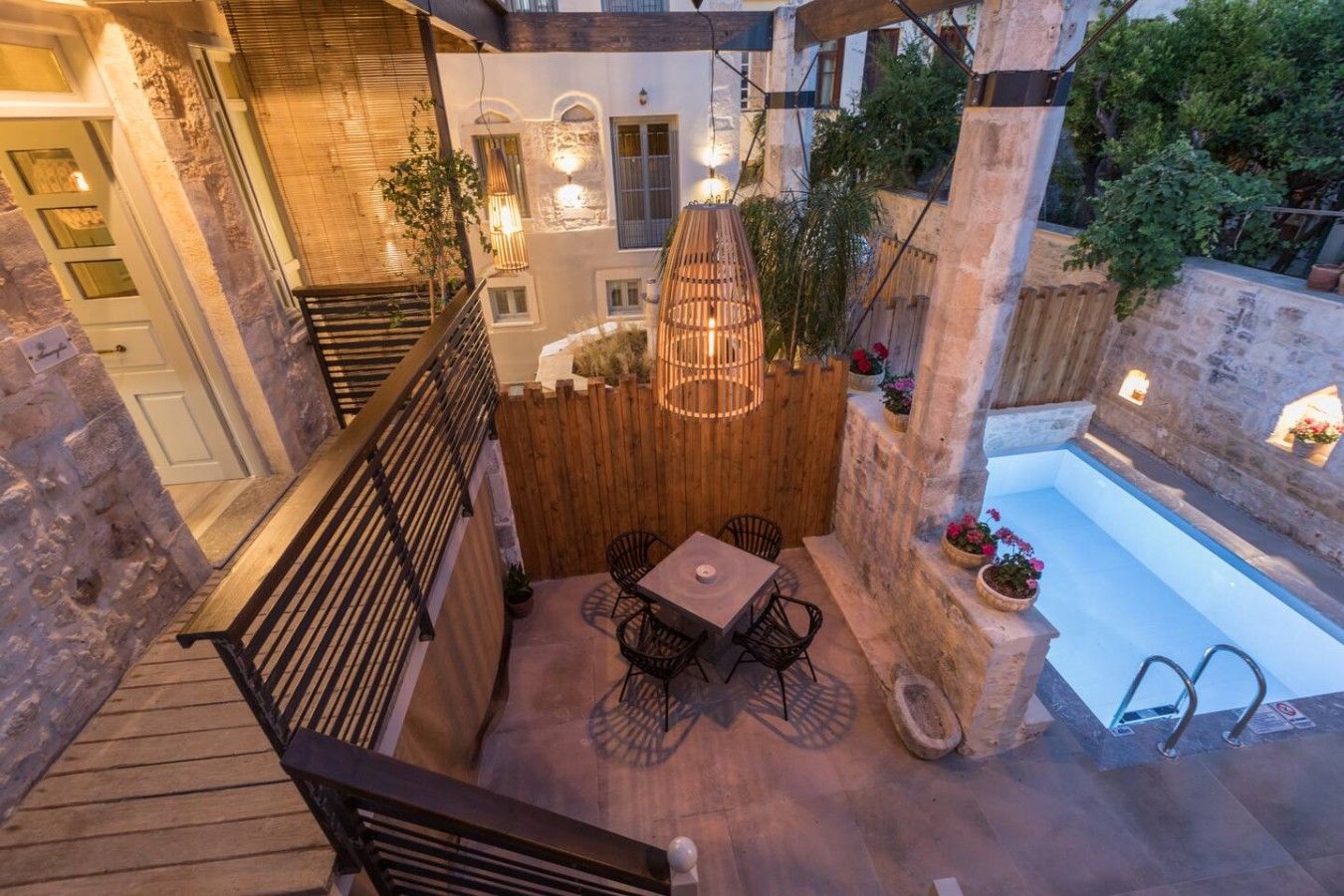 A rooftop patio with a pool, outdoor seating, and a wooden fence.