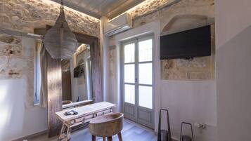 A bathroom with a stone wall, wooden floor, a wooden vanity, a hanging light fixture, and a large window.
