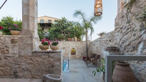 Un pati exterior amb parets de pedra, una piscina, plantes en testos i mobles de vimet.