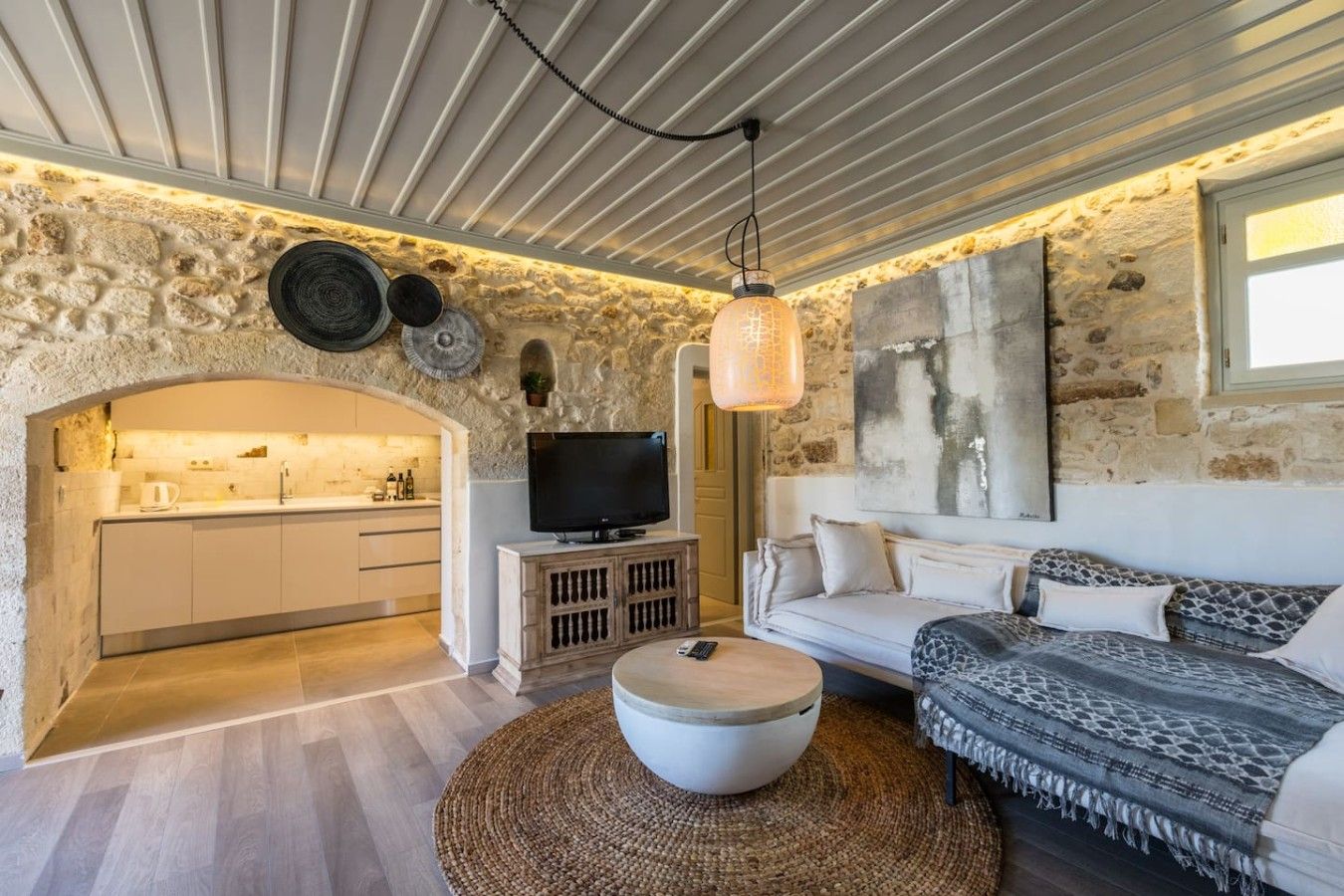 A cozy living room with a stone wall, a television, a sofa, and a coffee table.