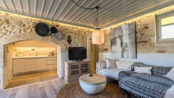 A cozy living room with a stone wall, a television, a sofa, and a coffee table.