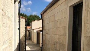 A narrow alleyway with buildings on either side, a window with a potted plant, and a clear blue sky. - House "Ile d'Aix" adapted PMR single center Rochefort (Rochefort)