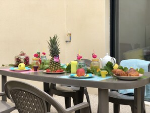 Mesa posta com frutas, bebidas e doces, sugerindo um arranjo para café da manhã ou lanche.