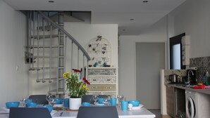 A modern kitchen with a built-in washing machine, a dining area with blue tableware, and a staircase with a metal railing. - House "Ile d'Aix" adapted PMR single center Rochefort (Rochefort)