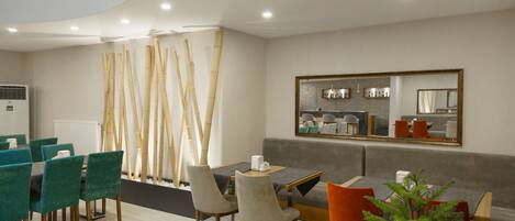 A modern dining area with a high ceiling, a central table, and seating arrangements.