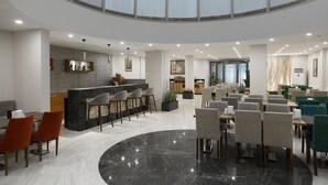 Un vestíbulo amplio con una zona de bar central, asientos y un tragaluz grande.