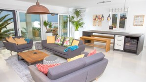 A modern living room with a grey sofa, wooden coffee table, and a dining area with a bench.